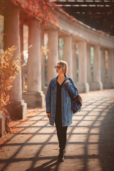 Mulher Elegante Jaqueta Ganga Óculos Andando Beco Com Colunas Hora — Fotografia de Stock