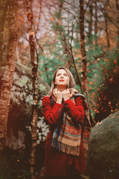 スカーフと岩と森のコートにかなり若い女性 山の秋シーズンの時間 — ストック写真