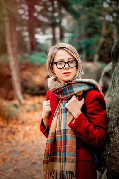 在森林与岩石的围巾和大衣的年轻妇女 在山的秋季季节时间 — 图库照片
