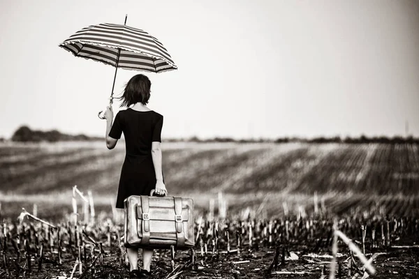 Молодая женщина с чемоданом и зонтиком — стоковое фото