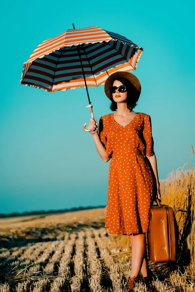 Jeune femme avec parapluie et valise — Photo