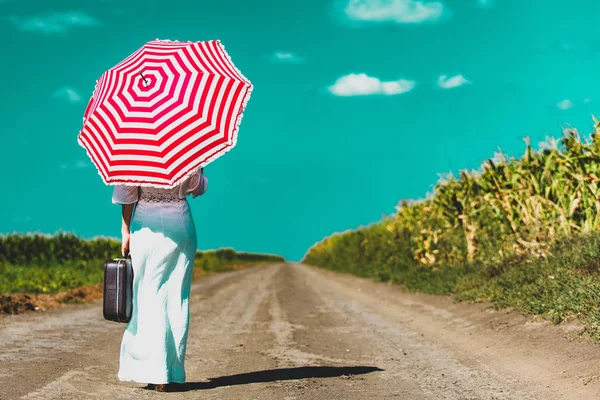 Jonge vrouw met koffer en paraplu — Stockfoto