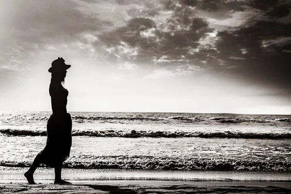 Woman in a hat walking on the beach — Stock Photo, Image