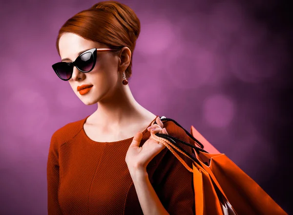 Rothaarige Frau Mit Einkaufstaschen Auf Lila Hintergrund — Stockfoto