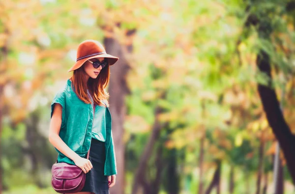 红发女孩在太阳镜和帽子在片秋色的公园 — 图库照片