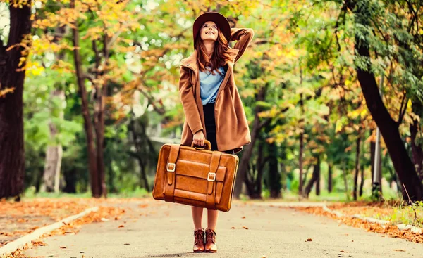 秋の公園でスーツケースで赤毛の女の子 — ストック写真