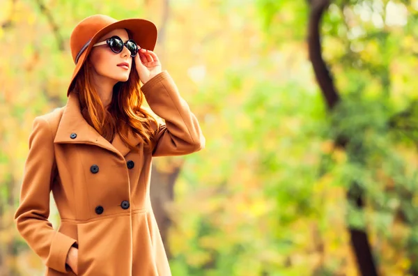 红发女孩在太阳镜和帽子在片秋色的公园 — 图库照片