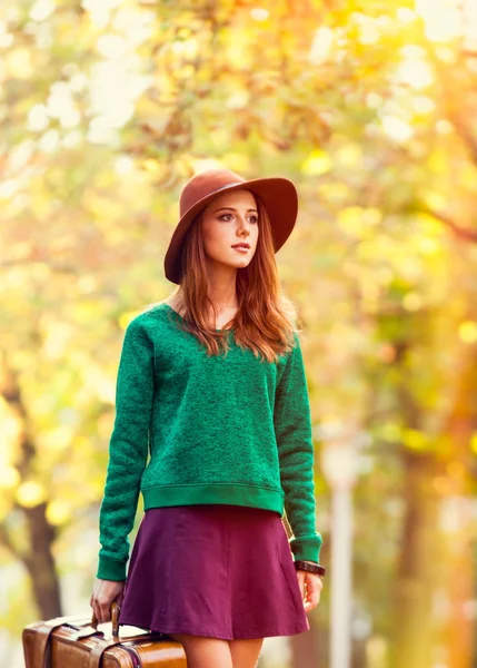 美丽的红发女孩绿色毛衣与手提箱在公园 — 图库照片