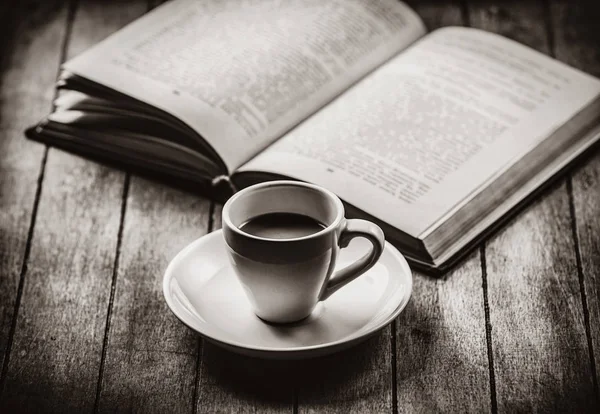 Filiżankę kawy i otwartej książki na drewnianym stole — Zdjęcie stockowe