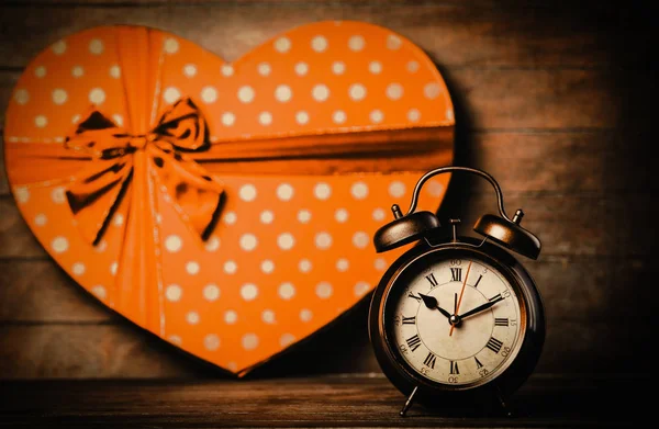 Alarm clock on the table with heart shape gift — Stock Photo, Image