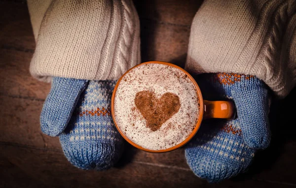 Hände in Fäustlingen mit einer Tasse Kaffee — Stockfoto