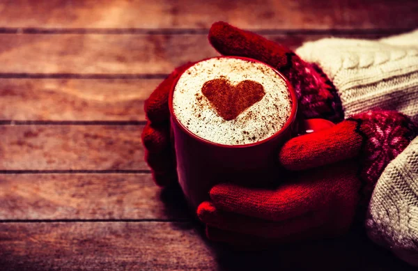 Hands in mittens holding hot cup of coffee — Stock Photo, Image