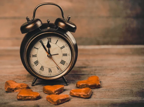 Retro alarm clock with cookie on a table — Stock Photo, Image