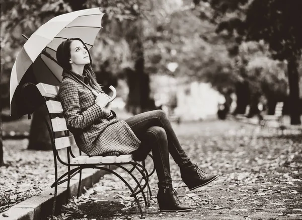Style girl sitting at bench in autumn park. — Stock Photo, Image