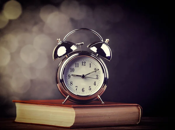 Metal alarm clock and open book. — Stock Photo, Image