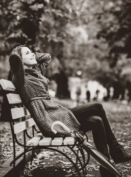Stil flicka sitter på bänken i höst park. — Stockfoto