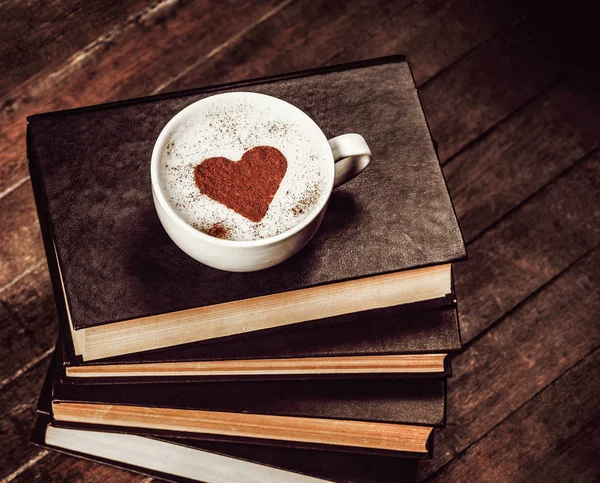 ถ้วยกาแฟที่มีสัญลักษณ์รูปหัวใจบนหนังสือ — ภาพถ่ายสต็อก