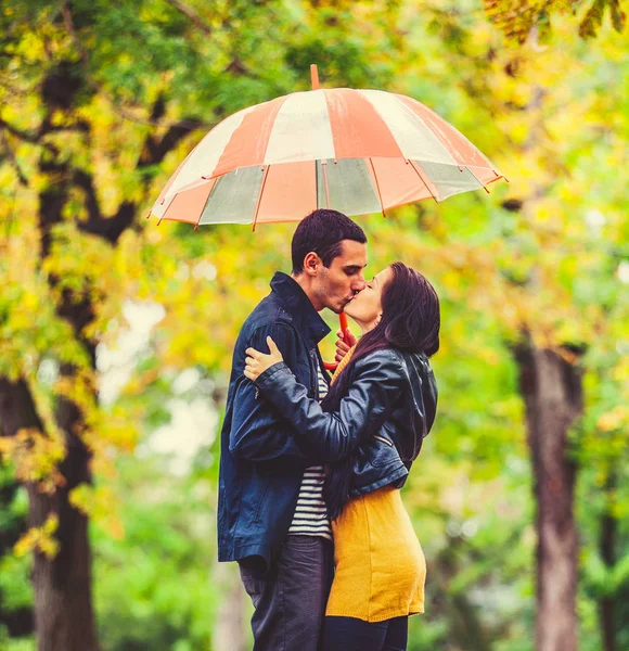 Ungt par i kärlek med paraply kyssar — Stockfoto