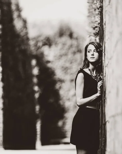 Mooie vrouw in zwarte jurk in de tuinen van versailles. — Stockfoto