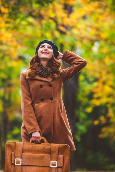 Zrzka dívka v baret a kabát s kufrem — Stock fotografie