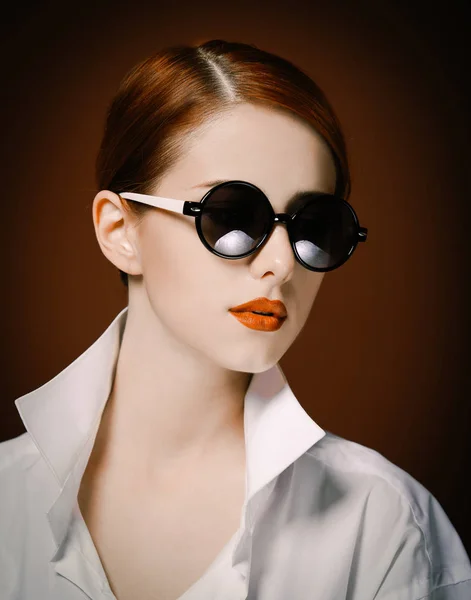 Стильная рыжая женщина в белой рубашке и солнечных очках — стоковое фото
