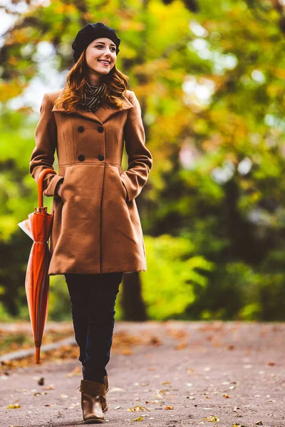 Рыжая девушка в пальто с зонтиком — стоковое фото