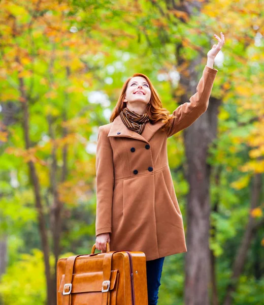 Ragazza rossa in berretto e cappotto con valigia — Foto Stock