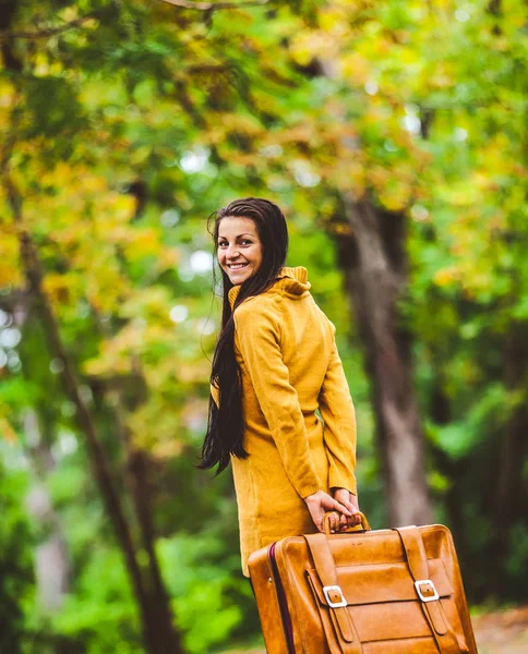 Девушка с чемоданом в осеннем переулке — стоковое фото