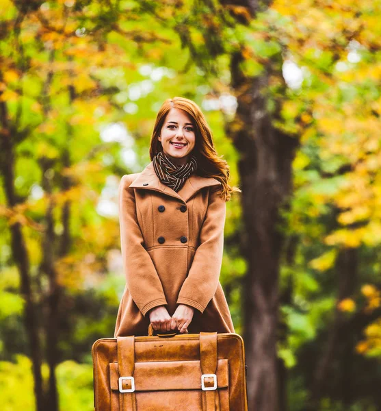 Rothaarige Mädchen in Baskenmütze und Mantel mit Koffer — Stockfoto