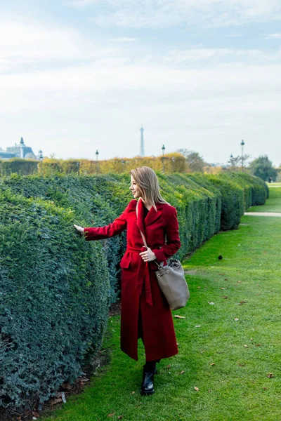Κορίτσι με το κόκκινο παλτό και τσάντα σε παριζιάνικο πάρκο — Φωτογραφία Αρχείου