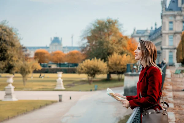 Dziewczyna w czerwonym płaszczu, z mapą, patrząc na park — Zdjęcie stockowe