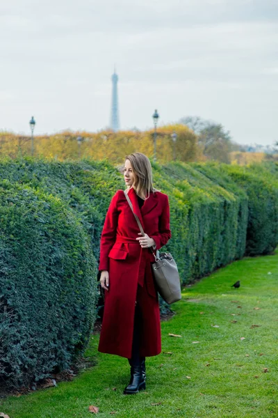 Menina em casaco vermelho e saco no parque parisiense — Fotografia de Stock