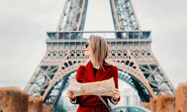 Flickan i röd kappa och väska med karta i parisisk park — Stockfoto