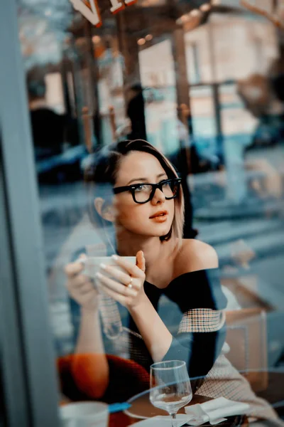 Dziewczyna w okularach z kubkiem kawy w paryskiej kawiarni — Zdjęcie stockowe