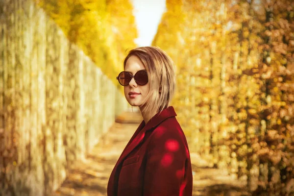 Mädchen mit Sonnenbrille und rotem Mantel im Park von Versailles — Stockfoto