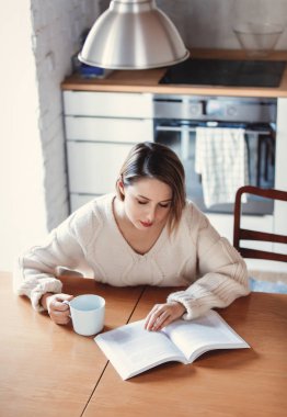 Beyaz kazaklı fincan kahve masada oturan kız