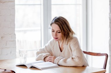 Kitap mutfak at ile beyaz süveterli yorgun kız