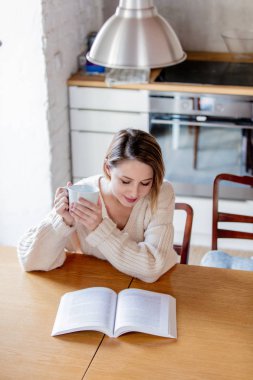 Beyaz kazaklı fincan kahve masada oturan kız
