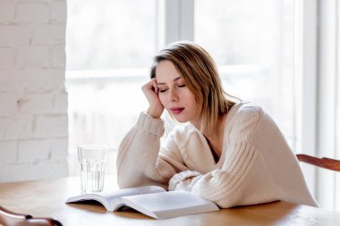 Kitap mutfak at ile beyaz süveterli yorgun kız