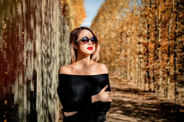 Flicka i solglasögon i höstsäsongen park — Stockfoto