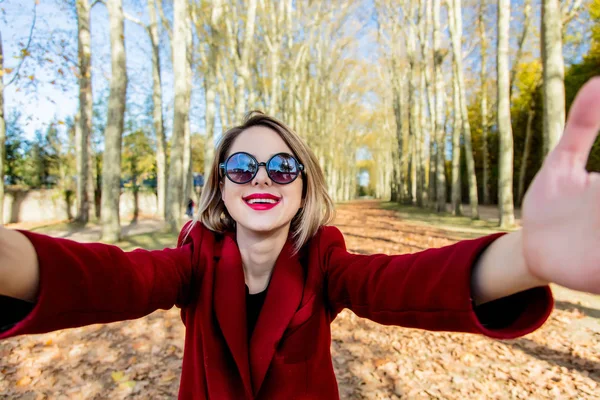 Девушка в солнечных очках и пальто в парке осеннего сезона — стоковое фото