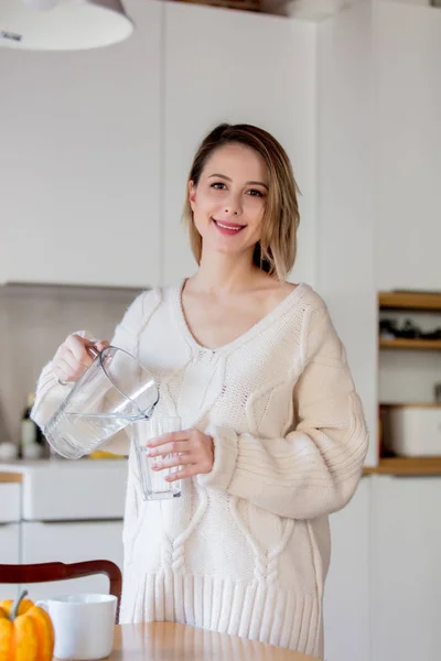 Young girl in sweater with glass of water at kitchen — Stock Photo, Image