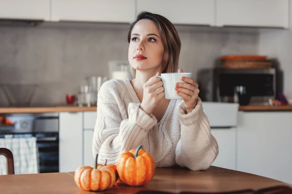 Bir fincan kahve tutarak ve masada oturan kız — Stok fotoğraf