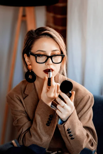 Menina em blazer e óculos aplicando maquiagem — Fotografia de Stock