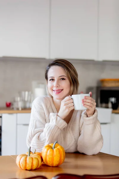 Girl holding a cup of coffee and sitting at table — Stock Photo, Image