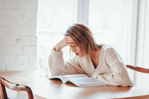 Ragazza stanca in maglione bianco con libro in cucina — Foto Stock