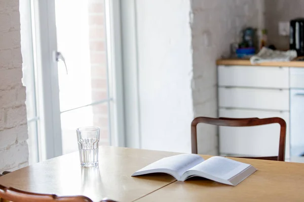 Aufgeschlagenes Buch und Glas Wasser auf Holztisch — Stockfoto