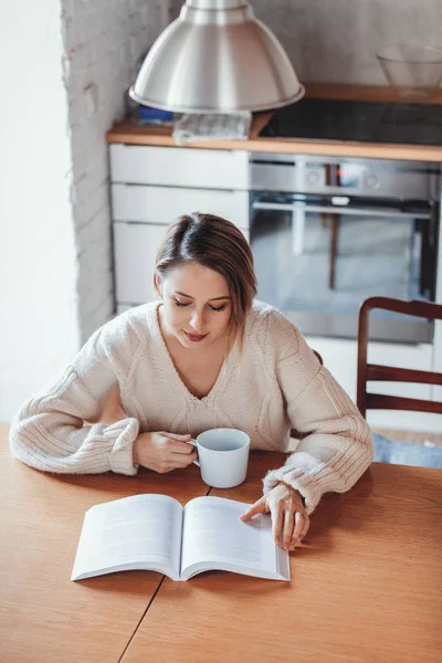 Chica en suéter blanco sentado en la mesa con taza de café —  Fotos de Stock