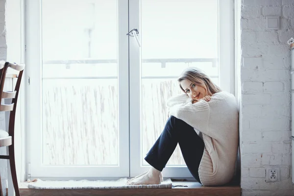 Girl dressed in a sweater is sitting at the threshold — Stock Photo, Image