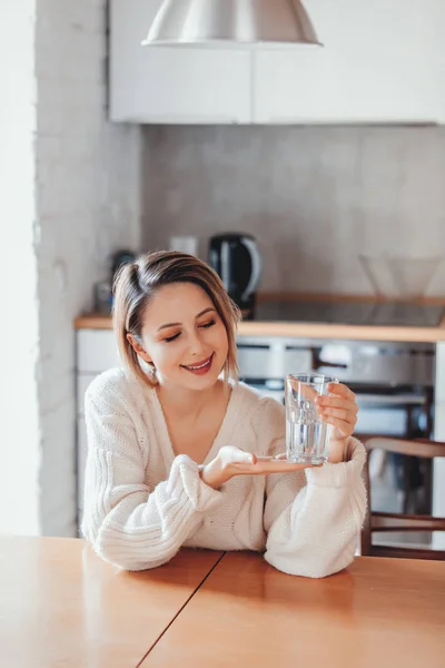 Chica joven en suéter con vaso de agua —  Fotos de Stock
